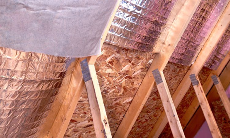 Inside gable and joist view of ongoing project, insulation of attic with fiberglass cold barrier and reflective heat barrier between the attic joists. Source: Shutterstock.